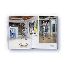 Load image into Gallery viewer, A colorful, abstract artwork as a statue featured on a page of a paperback book titled 'The elephant never forgets' by Danny Minnick.